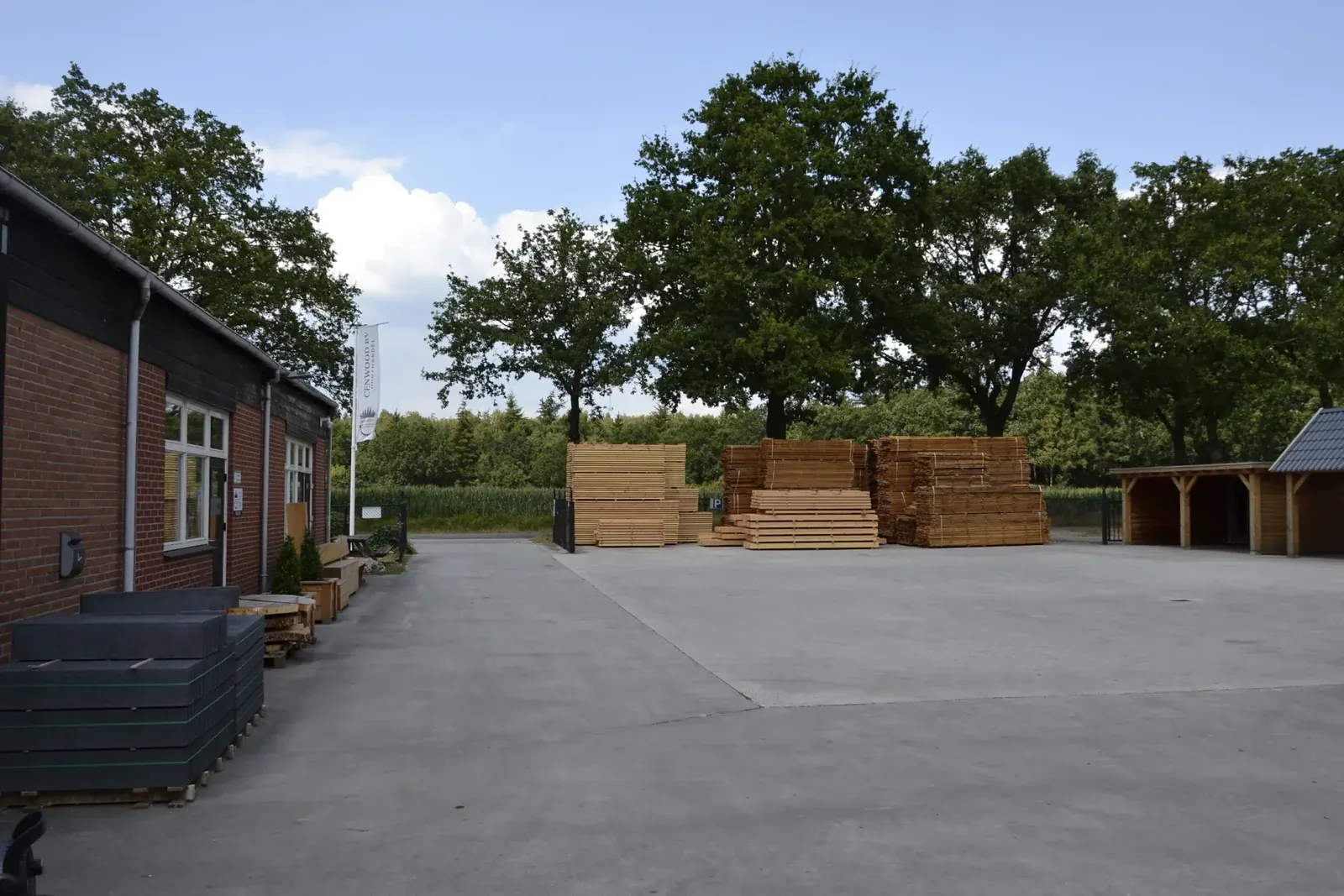 Het buitenterrein van houthandel CenWood in Gemert met bedrijfspand en stapels douglas hout