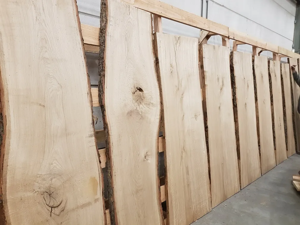 Eiken boomstamplanken rechtop in het rek, met prijzen per plank bij CenWood