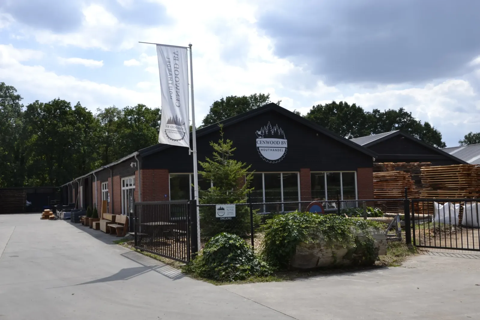 Het bedrijfspand van houthandel CenWood in Gemert met vlaggenmast en houtvoorraad op het terrein