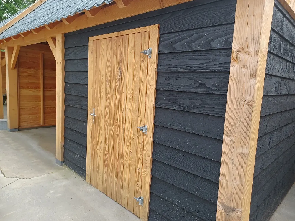 Antraciet tuinhuis met zadeldak en douglas deur, afgewerkt met houten hoekstijlen
